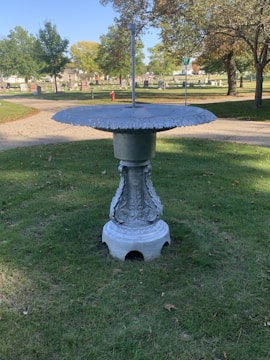 A sturdy concrete birdbath with intricate leaf designs.