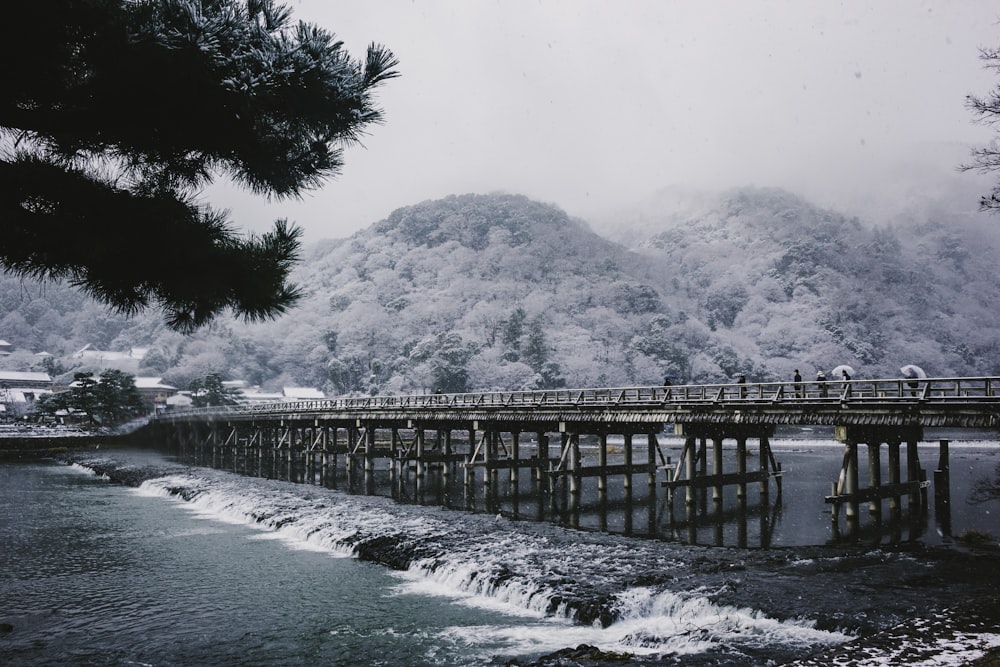 uma ponte sobre um corpo de água com uma montanha ao fundo