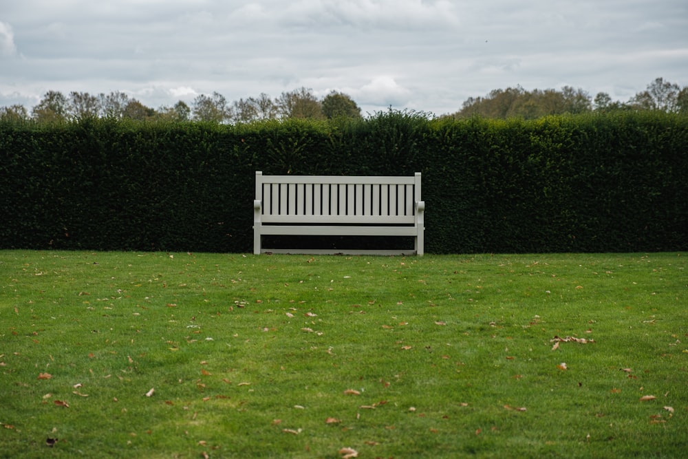a white bench sitting on top of a lush green field