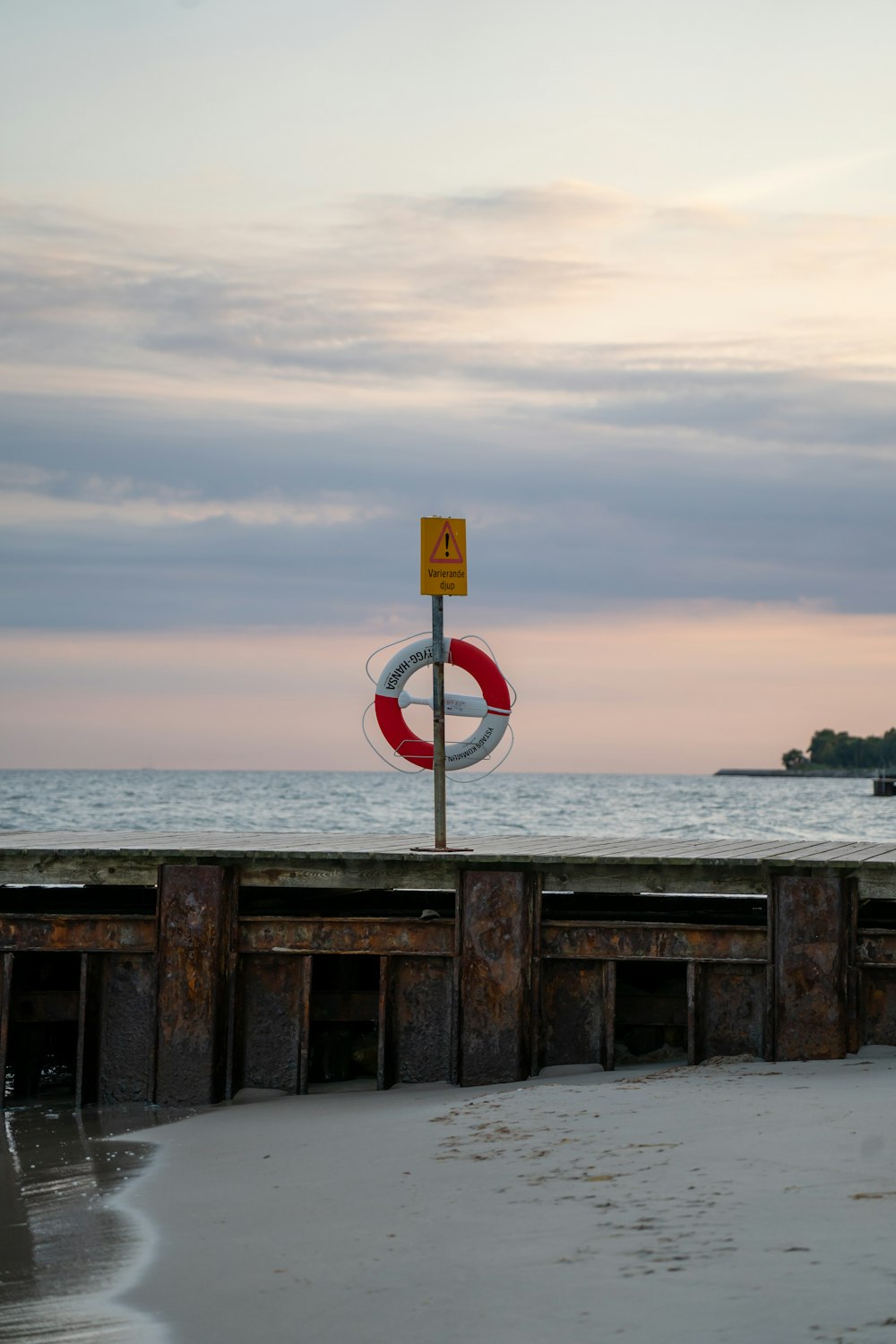 a red and white sign sitting on the side of a beach