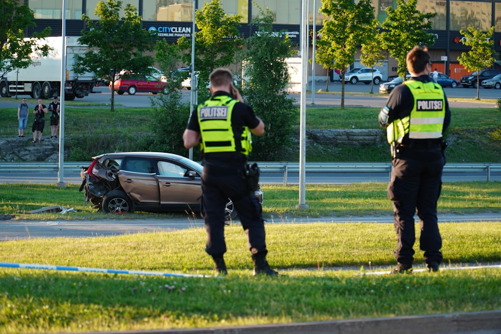 Police officers in front of a crashed car.