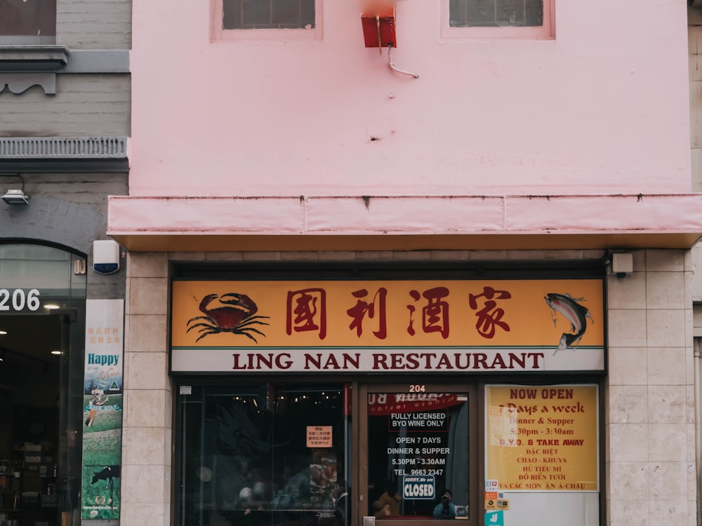 a chinese restaurant with a pink building and a red umbrella