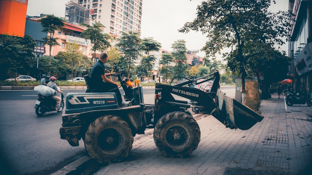 a man riding on the back of a tractor down a street