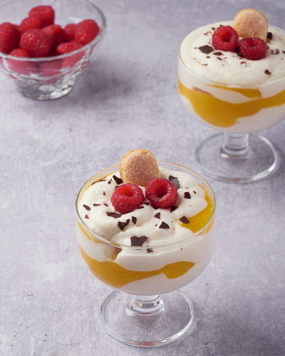 two desserts with raspberries on top of them