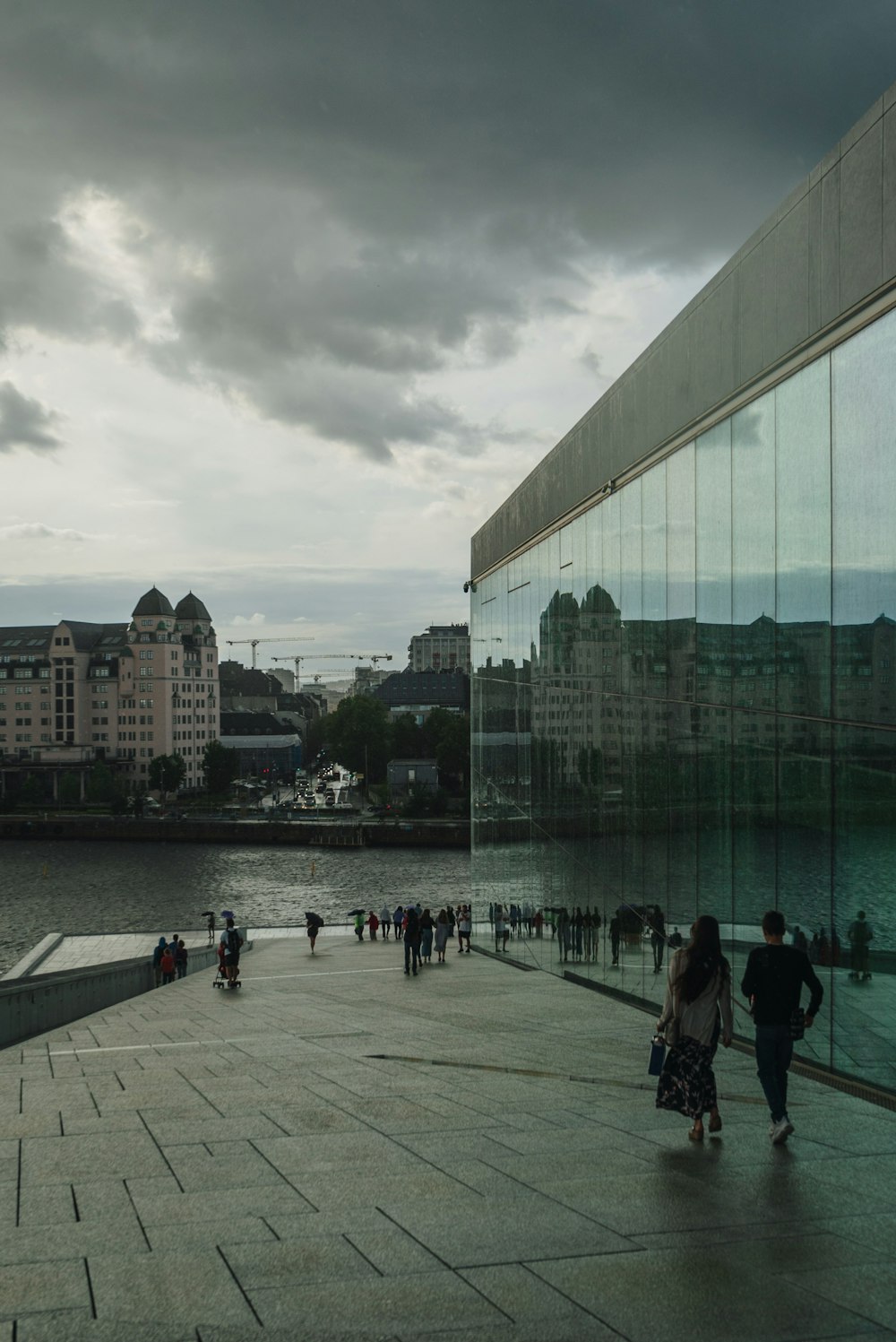 a group of people walking on a sidewalk next to a body of water