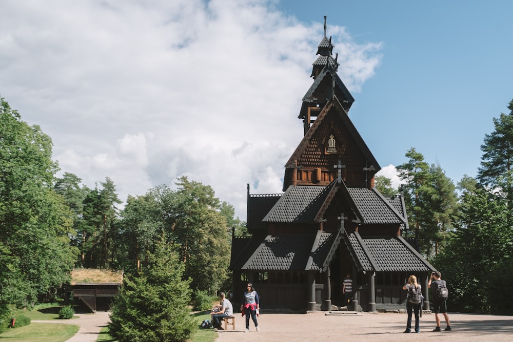 a group of people standing in front of a wooden church