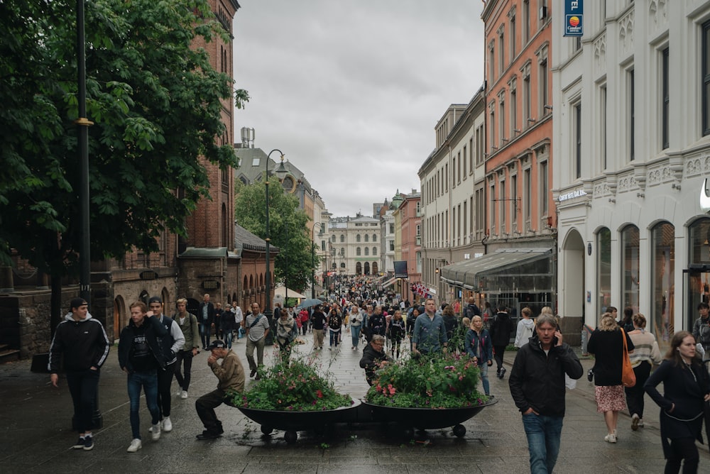 a crowd of people walking down a street next to tall buildings