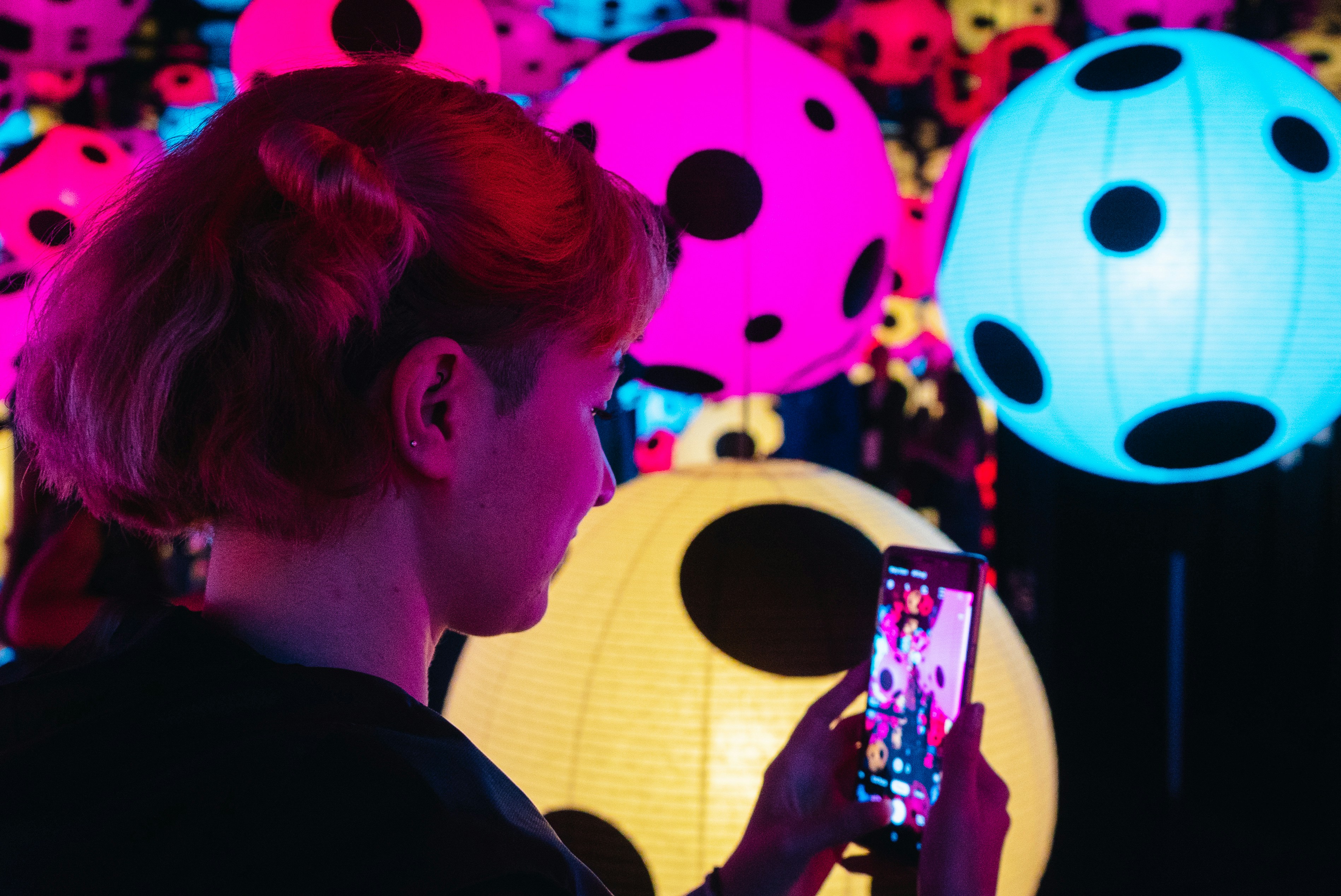 a woman taking a picture of a display of colorful lights, 