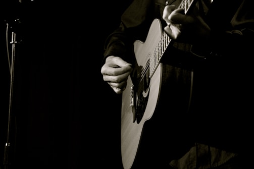 Close-up of hands strumming an acoustic guitar during an intimate live set.
