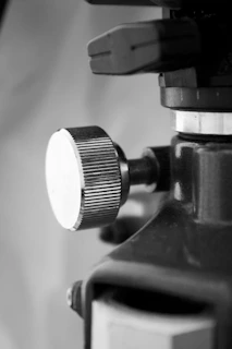 Close-up of a hand adjusting a sleek metallic control knob on a futuristic machine against a dark industrial background.