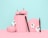 Pastel pink pumpkins are arranged creatively alongside a scalloped frame and black eyeliner pens. White ghost decorations add a whimsical and spooky touch against the soft blue background.