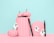 Pastel pink pumpkins are arranged creatively alongside a scalloped frame and black eyeliner pens. White ghost decorations add a whimsical and spooky touch against the soft blue background.