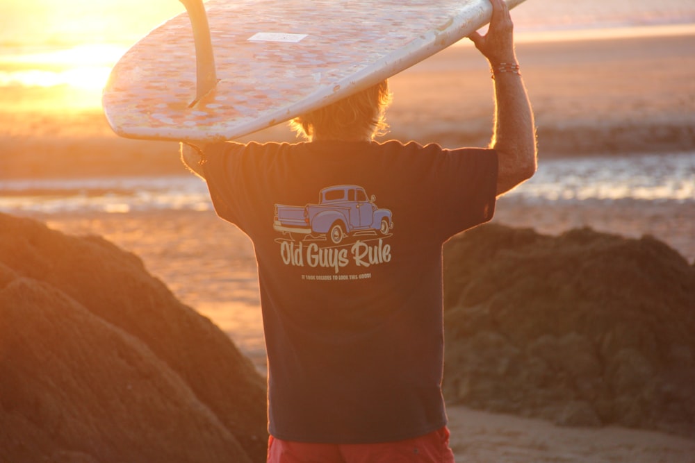 Un hombre sosteniendo una tabla de surf en la parte superior de su cabeza
