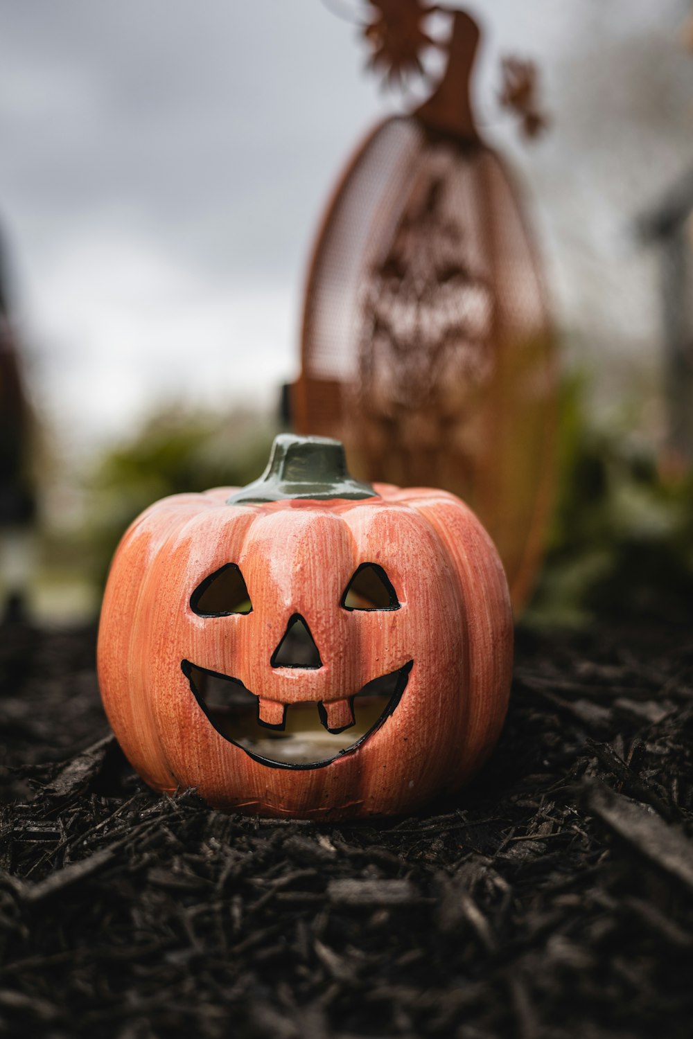 a carved pumpkin sitting on the ground next to a bottle