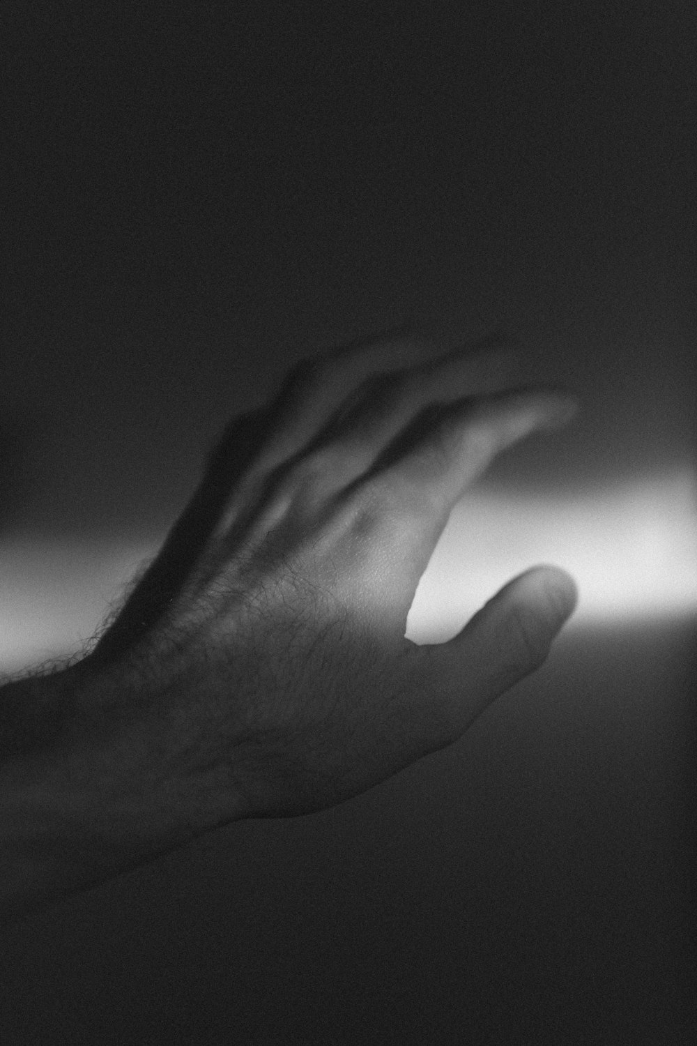 a black and white photo of a hand reaching for something