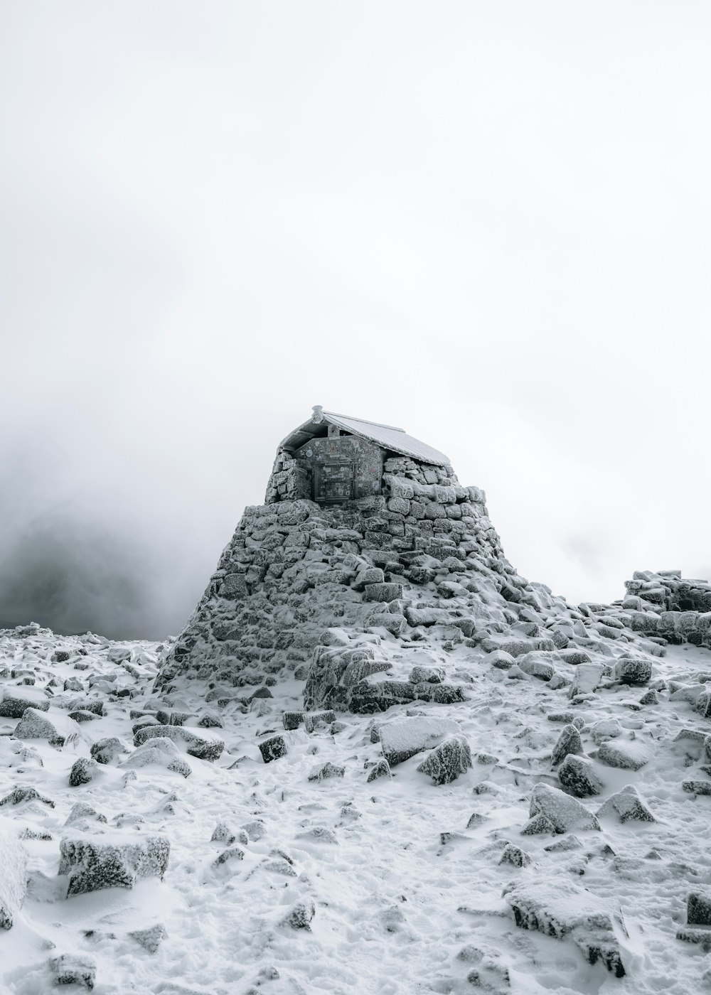 a snowy mountain with a small structure on top of it