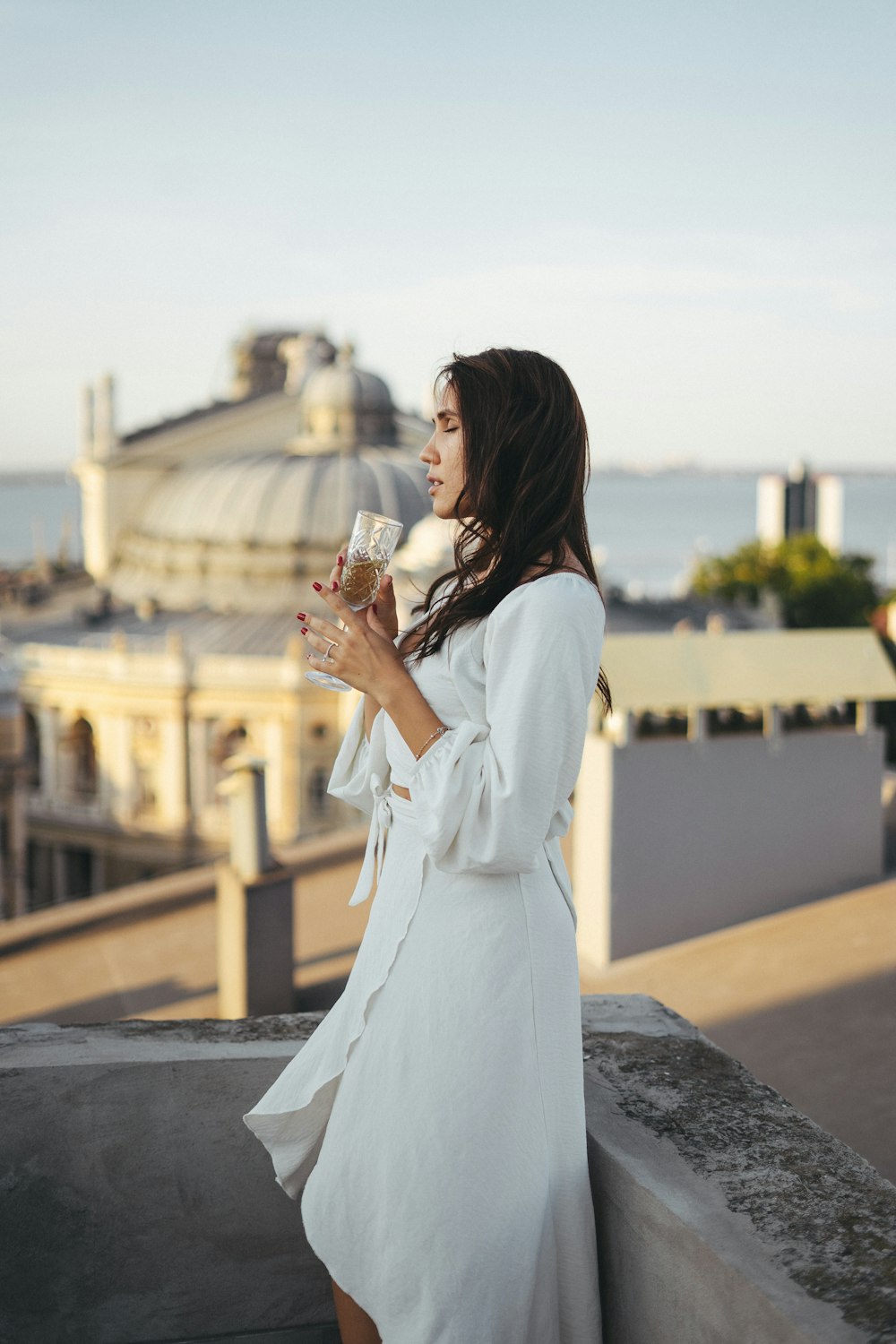 a woman in a white dress holding a glass of wine