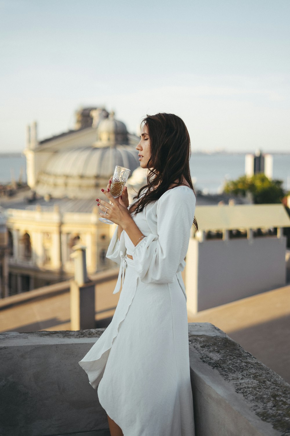uma mulher em um vestido branco segurando um copo de vinho