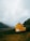 a yellow house sitting on top of a lush green hillside