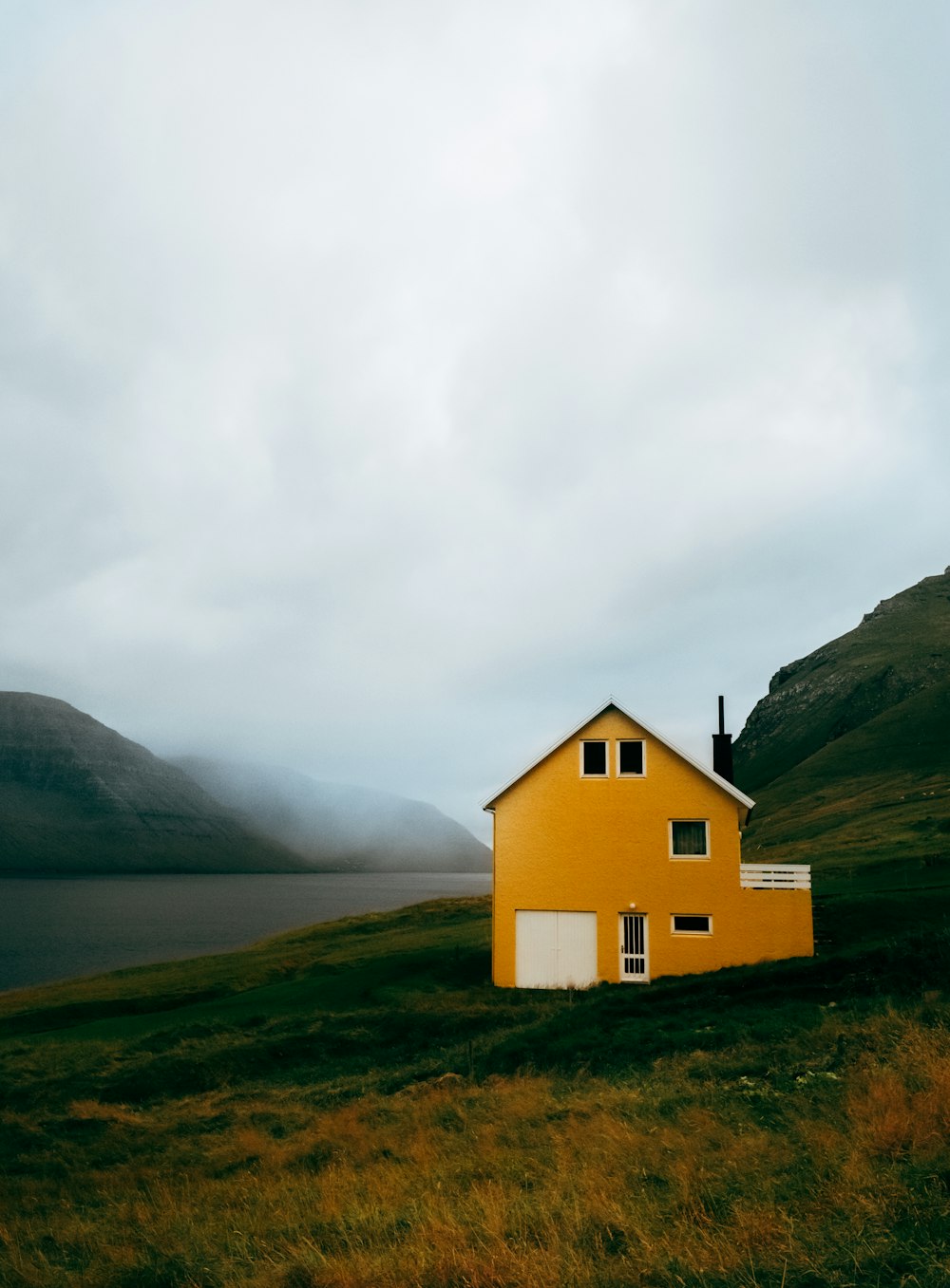 a yellow house sitting on top of a lush green hillside
