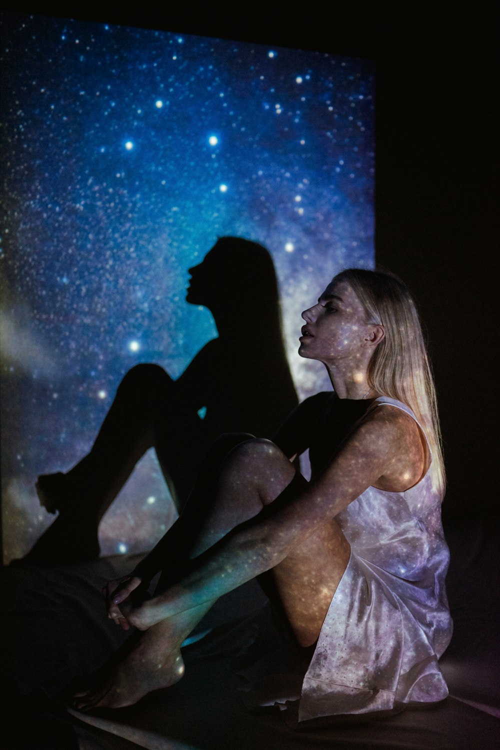 a woman sitting on a bed in front of a projection