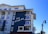 A modern coastal hotel building with a mixture of dark blue and white exterior. The building features multiple balconies with railings and large windows. The sign on the building reads 'The Seabird.' The sky is clear and blue, contributing to a serene atmosphere.
