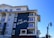 A modern coastal hotel building with a mixture of dark blue and white exterior. The building features multiple balconies with railings and large windows. The sign on the building reads 'The Seabird.' The sky is clear and blue, contributing to a serene atmosphere.