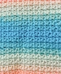 A close-up view of a crocheted fabric with a pattern of alternating colors. The texture shows a consistent and repetitive stitching pattern, transitioning smoothly from light blue to various shades of green and finally to peach.