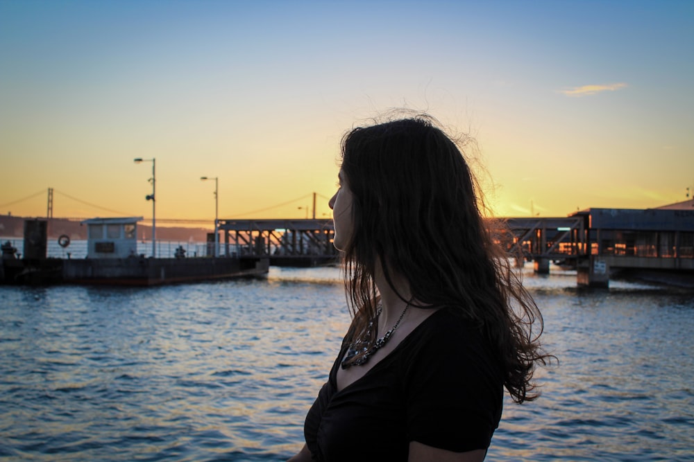 a woman standing in front of a body of water