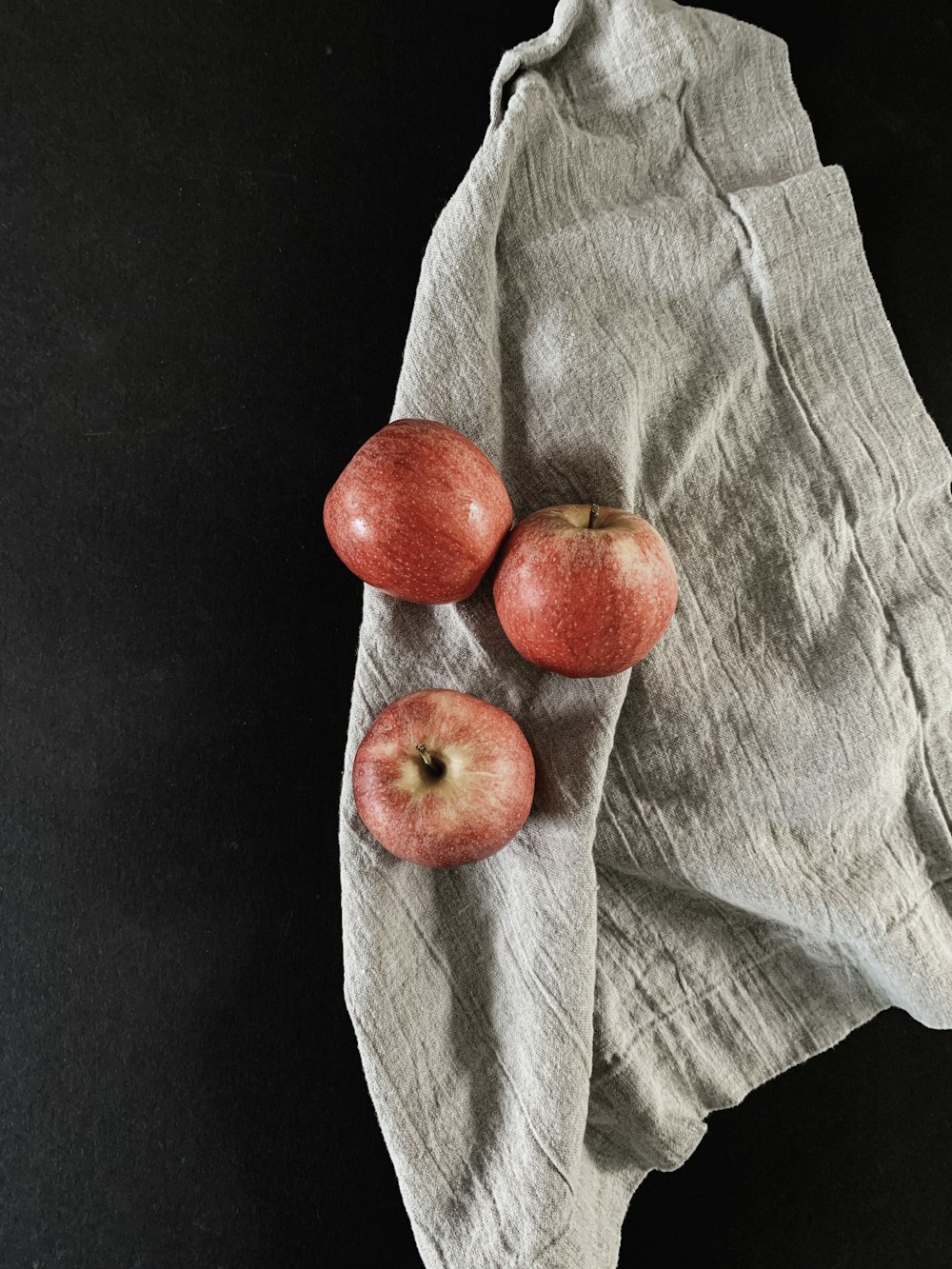 three apples sitting on top of a piece of cloth
