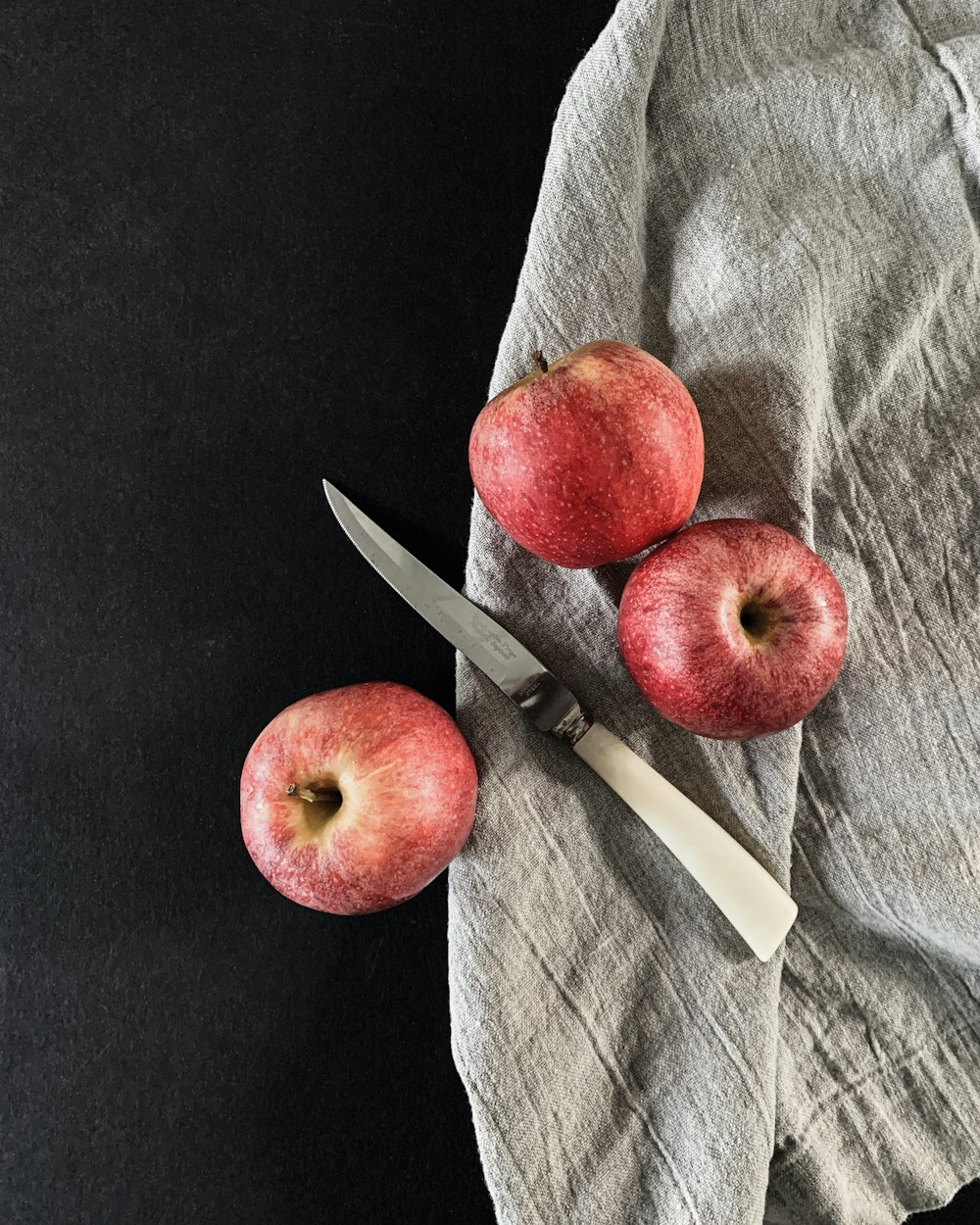 a pair of apples sitting on top of a table next to a knife