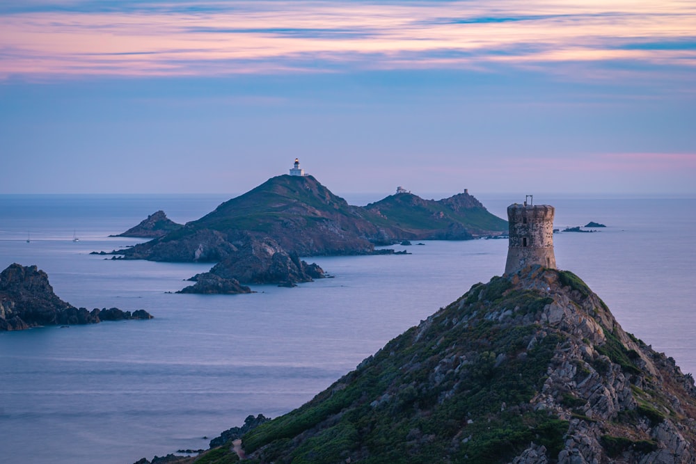 a lighthouse on top of a small island in the middle of the ocean