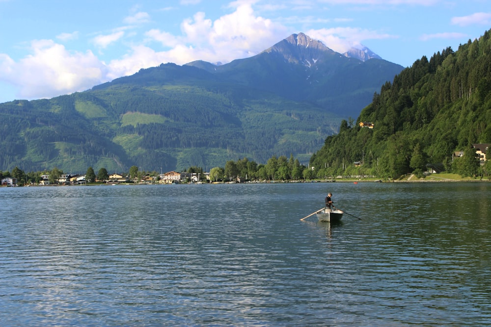 a person on a boat in a lake with mountains in the background