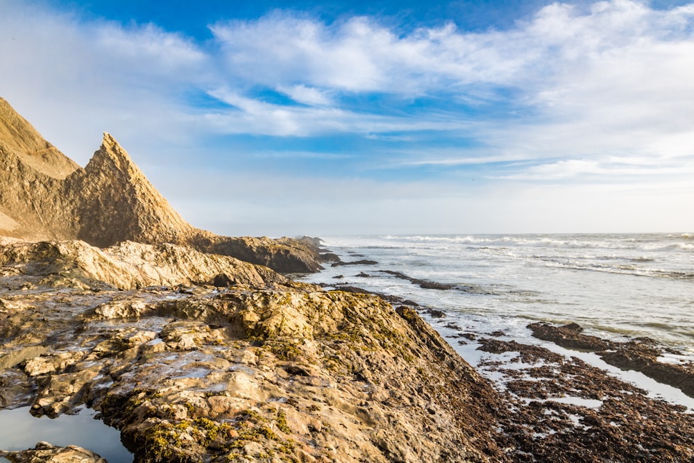 a view of a rocky beach with a mountain in the background