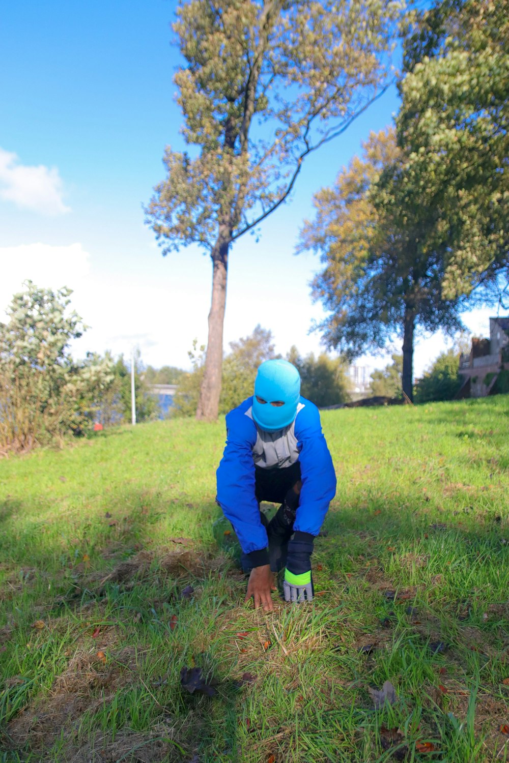 a person in a blue jacket crouching down in the grass