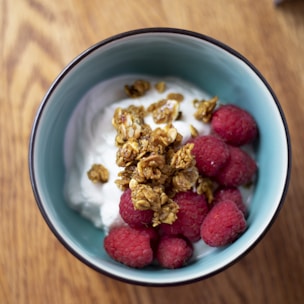An assortment of colorful yogurt cups with fresh fruit and granola on a rustic wooden table.