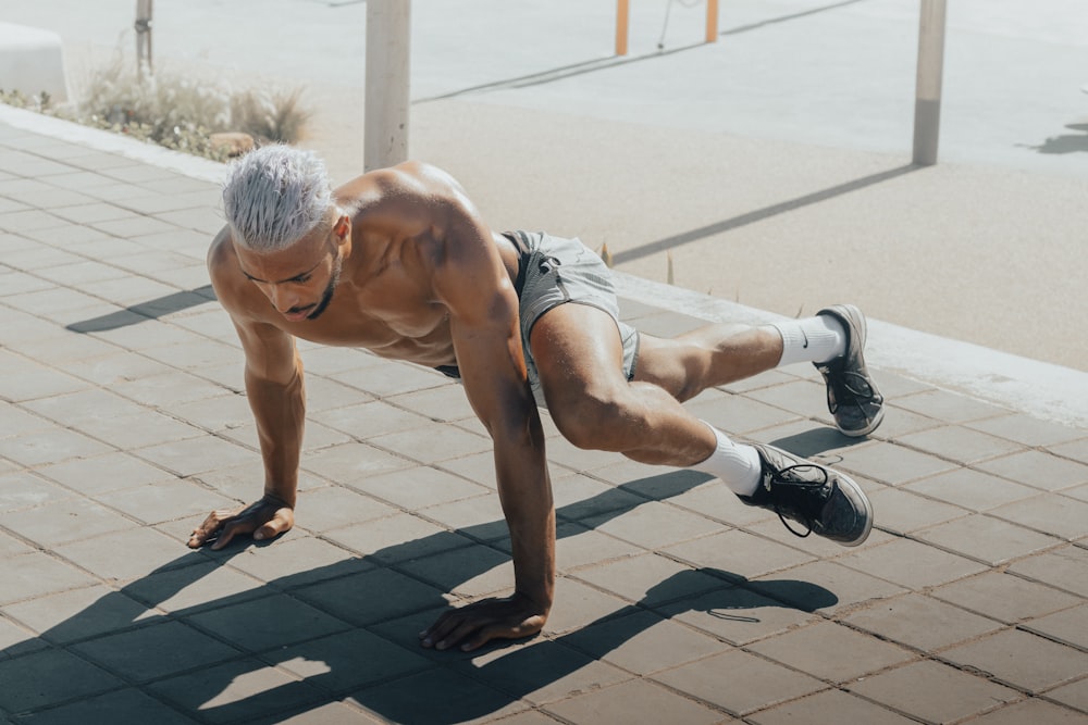 a man doing push ups on a brick sidewalk