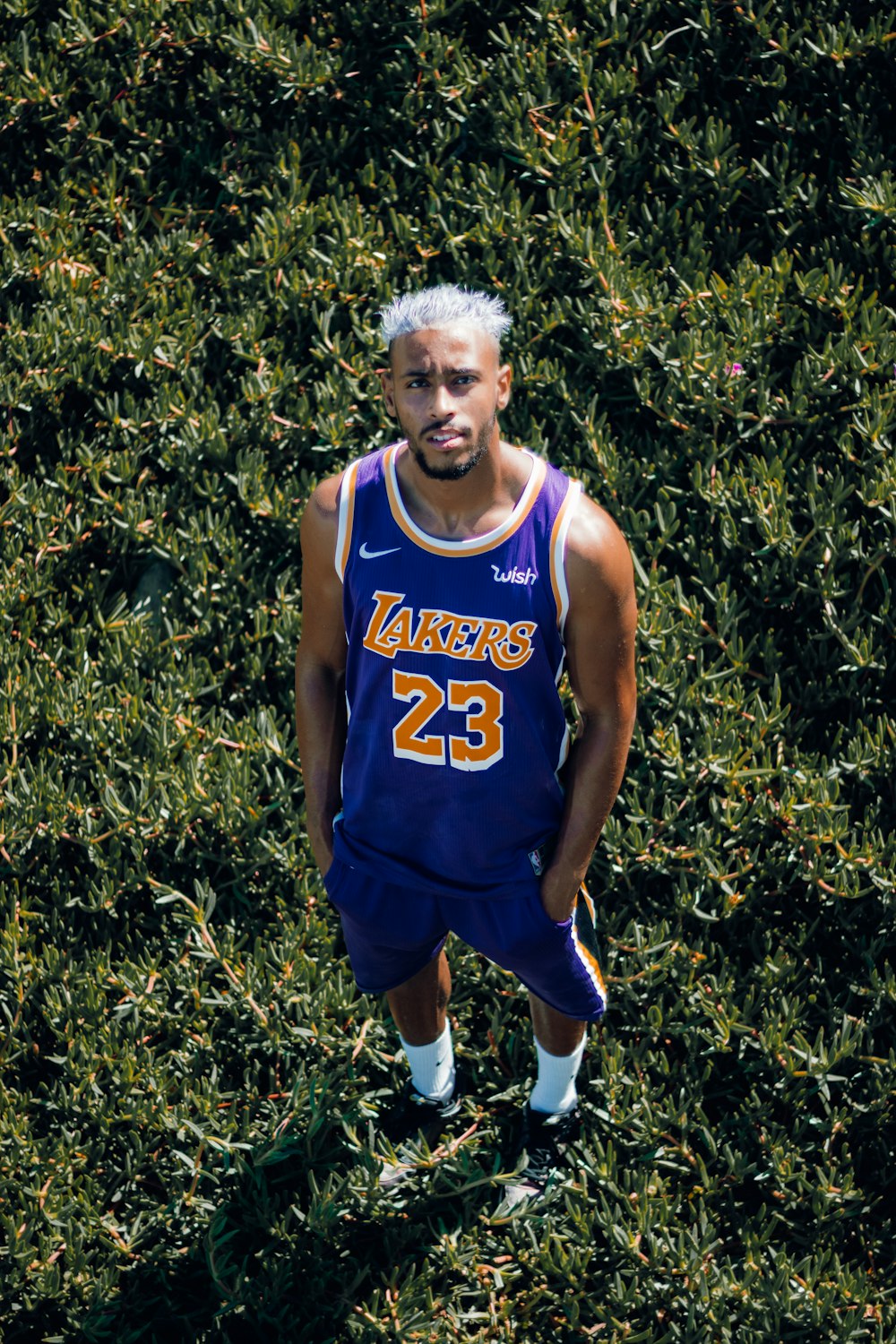 a man in a basketball uniform standing in front of a bush