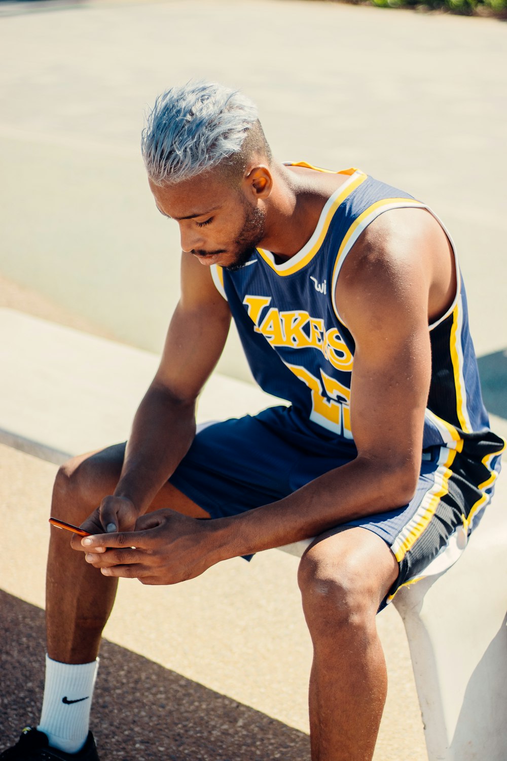 a man sitting on a bench wearing a basketball uniform