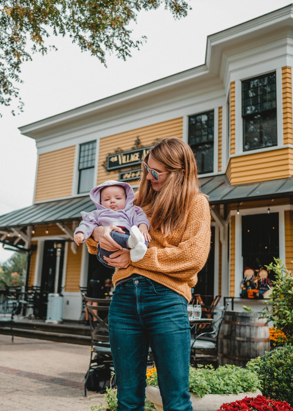 a woman holding a baby in front of a building