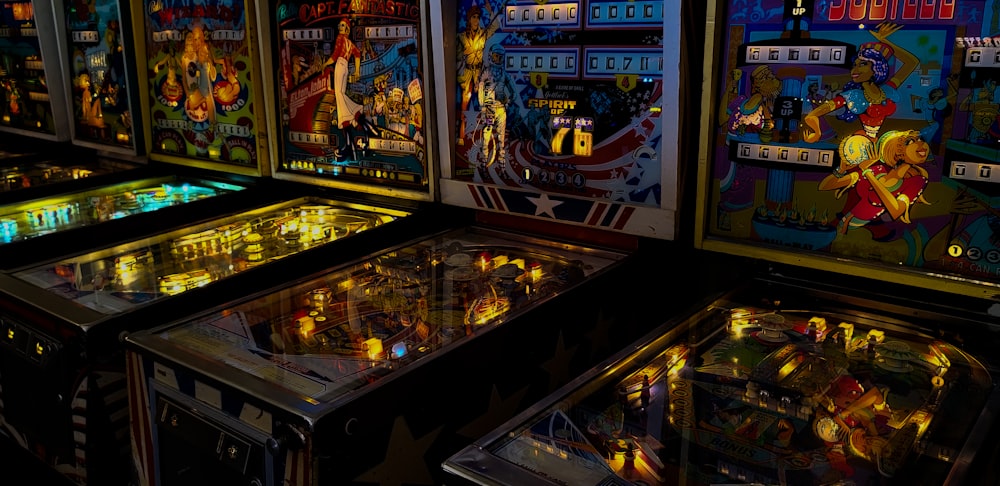 uma fileira de máquinas de pinball sentadas uma ao lado da outra