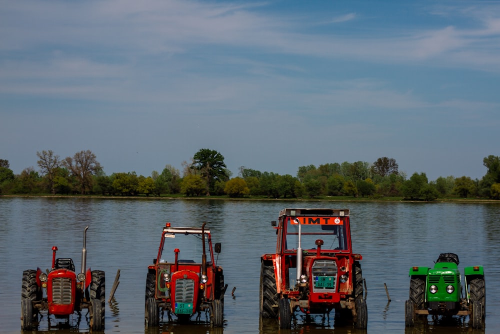 a group of four tractors sitting in the water