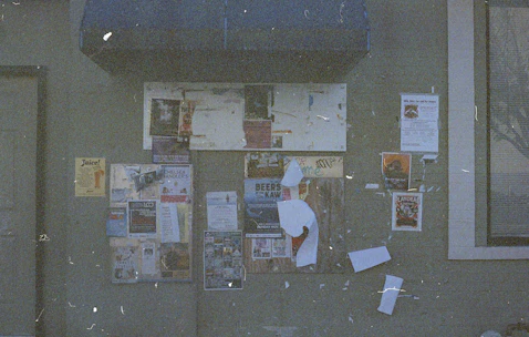 Students and teachers gathered around a bulletin board filled with education news and announcements.