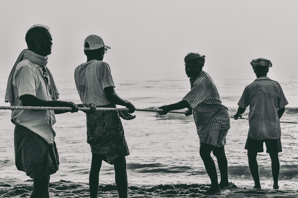 a group of men standing on top of a beach next to the ocean