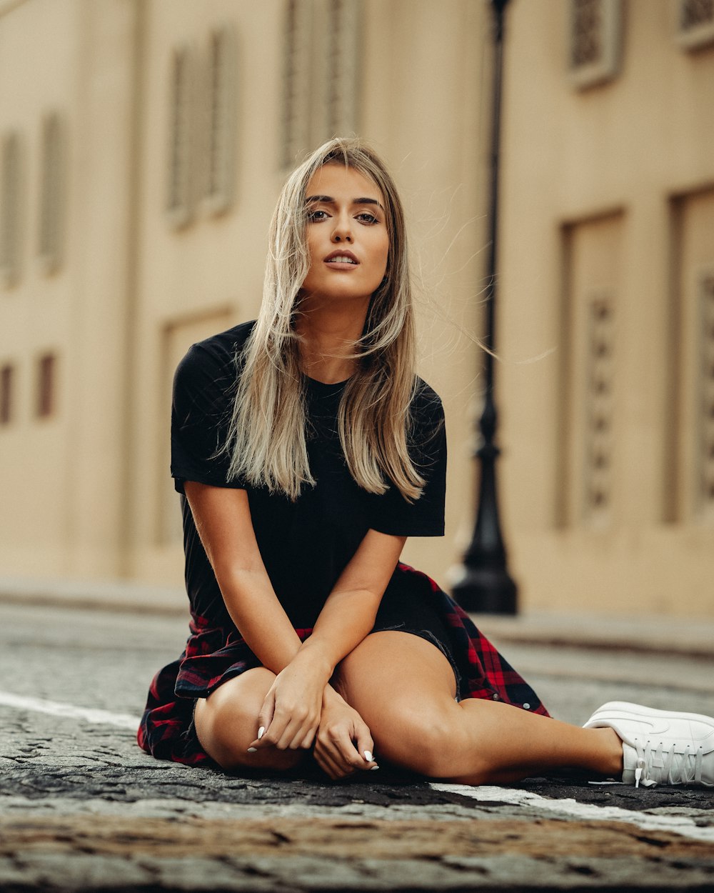 a woman sitting on the ground in front of a building