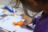 a little girl is cutting carrots on a board