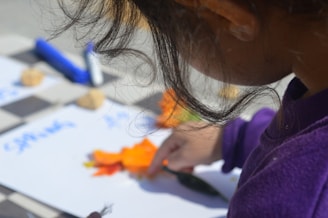 a little girl is cutting carrots on a board