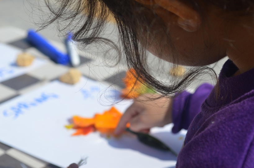 a little girl is cutting carrots on a board