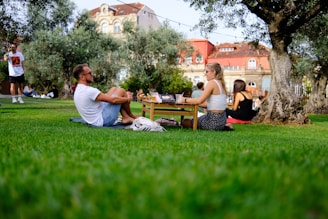 a man and a woman sitting on the grass in a park