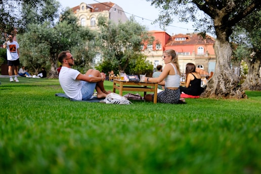 a man and a woman sitting on the grass in a park